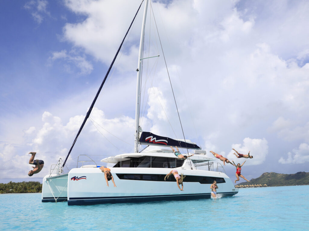 People jumping off a Moorings charter catamaran