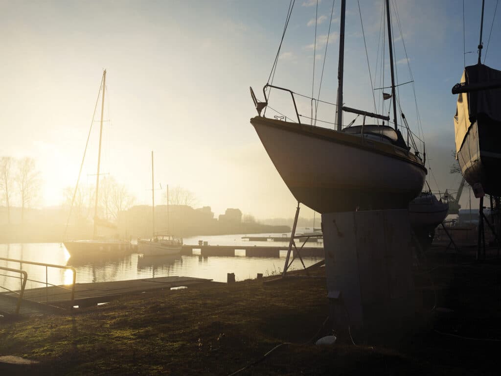 Winterized sloop rigged yacht standing on land, close-up.